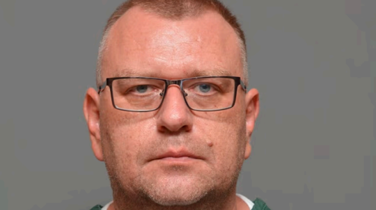 A headshot shows a man with short hair and glasses, wearing a green striped shirt, looking directly at the camera with a neutral expression.