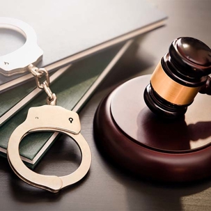 A professional image featuring silver handcuffs and a wooden gavel, resting on legal books, symbolizing law and justice.